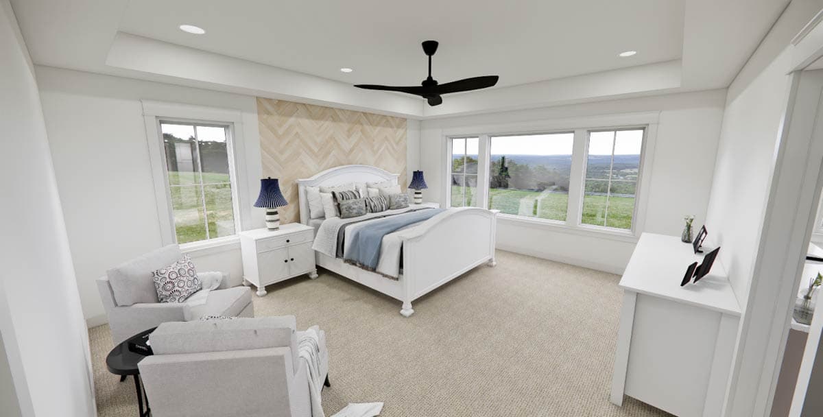A bright bedroom features a white bed, bedside tables with lamps, and two armchairs. Large windows offer a view of the outdoors.