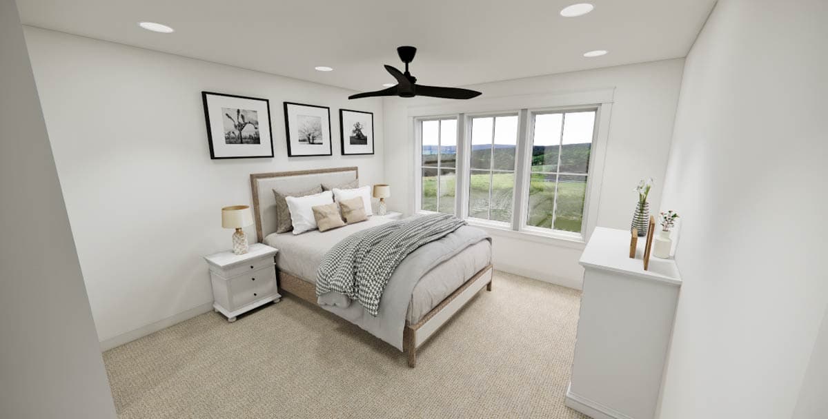 A modern bedroom with a bed, nightstands, and framed art. Large windows offer a view of a green landscape. A ceiling fan hangs above the bed.