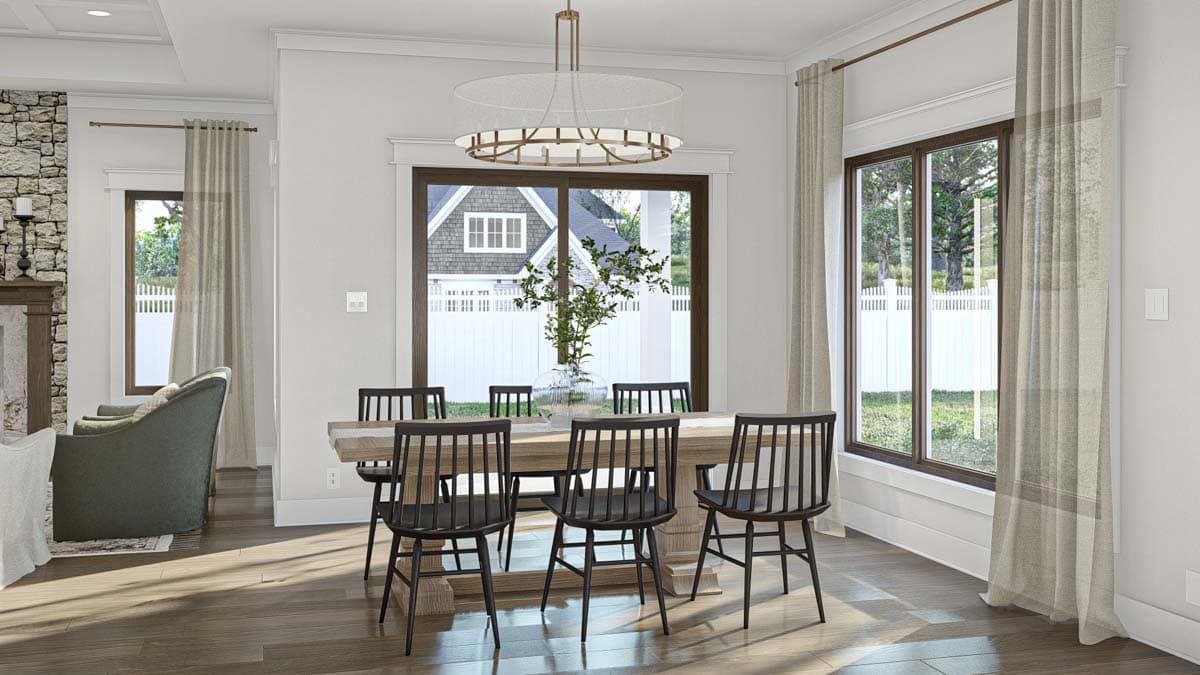 Dining area with wooden table and chairs, large window, and stone fireplace accent.