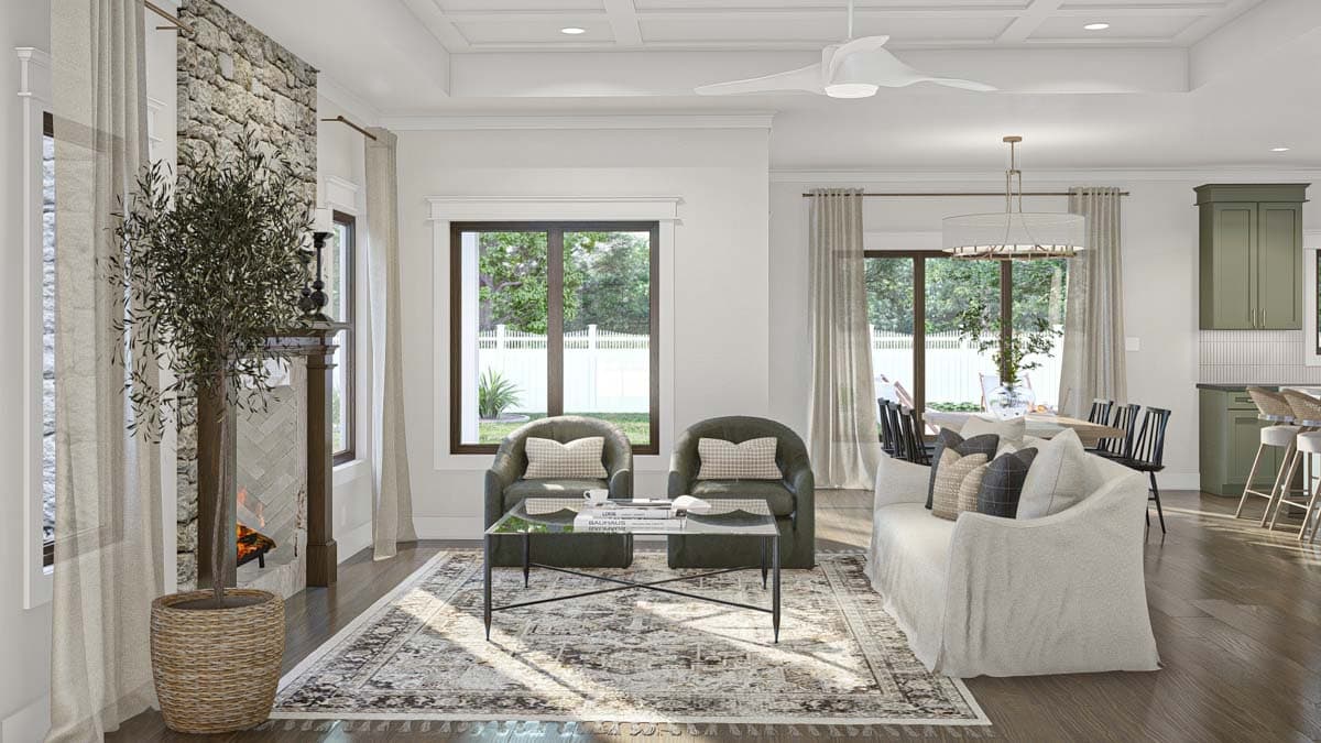 Interior view of a living room with stone fireplace, coffered ceiling, and open access to a dining area and kitchen.