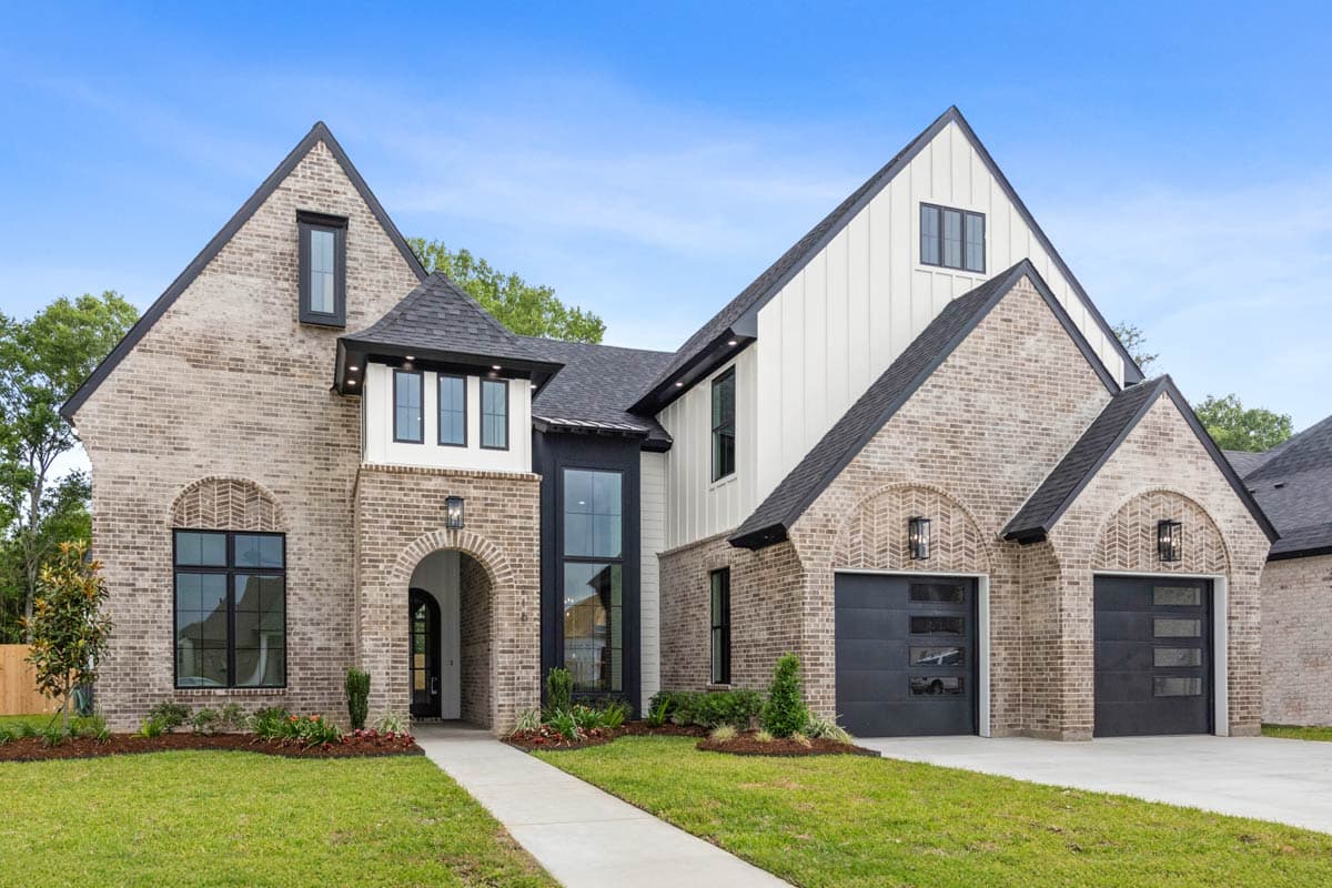House plan exterior with brick facade, arched entry, gabled rooflines, vertical siding, and a three-car garage.