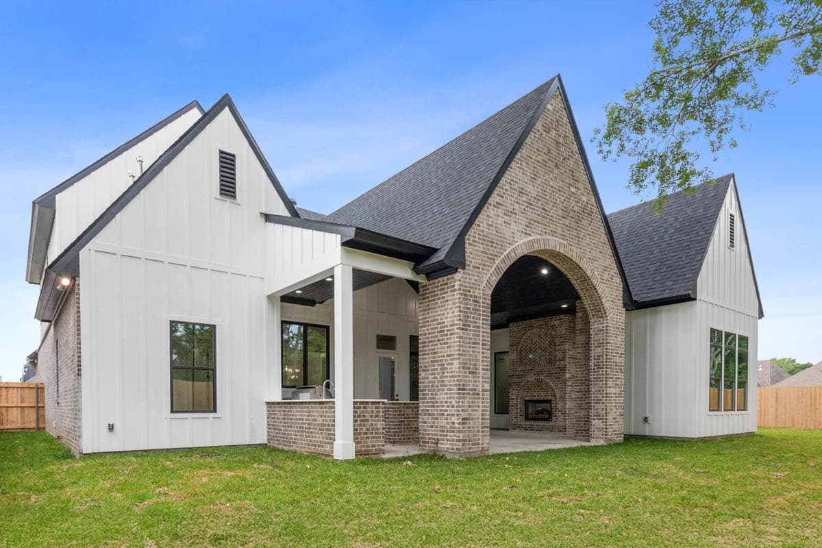 Modern Farmhouse house plan exterior with gabled roofs, white board and batten siding, brick accents, and arched outdoor fireplace.