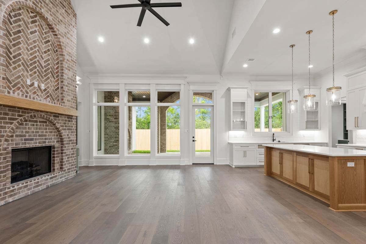 Interior view: Great room with vaulted ceiling, large brick fireplace, and kitchen island. Open layout.