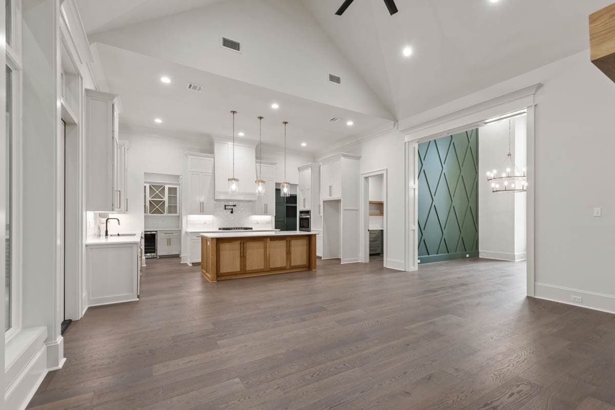 Open-concept kitchen and great room with vaulted ceiling, wood island, and decorative accent wall.