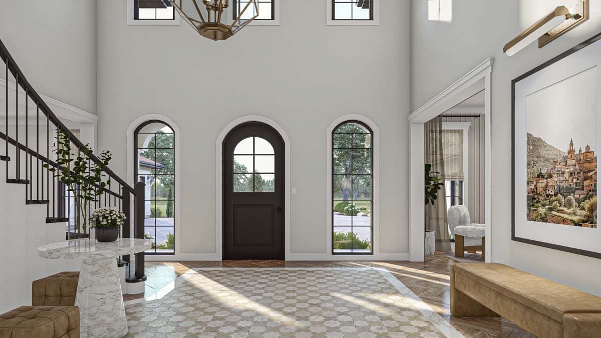 Foyer with arched entry door, arched windows, curved staircase with iron railing, patterned floor tiles and hardwood flooring.