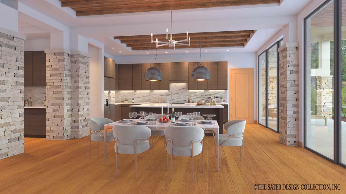 Dining area with stone-clad columns and kitchen with island, open to large glass doors. Wooden ceiling beams and floors.