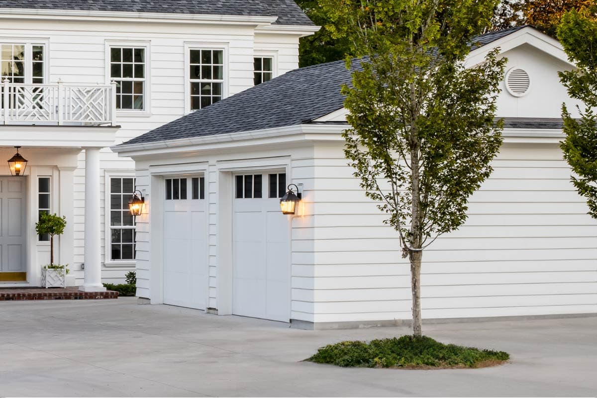 House plan exterior featuring a two-story design with a garage, gabled roof, and a front porch with a balcony.