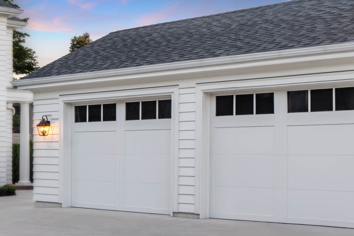 House plan exterior: Two-car garage with white paneled doors featuring upper windows and traditional lantern light.