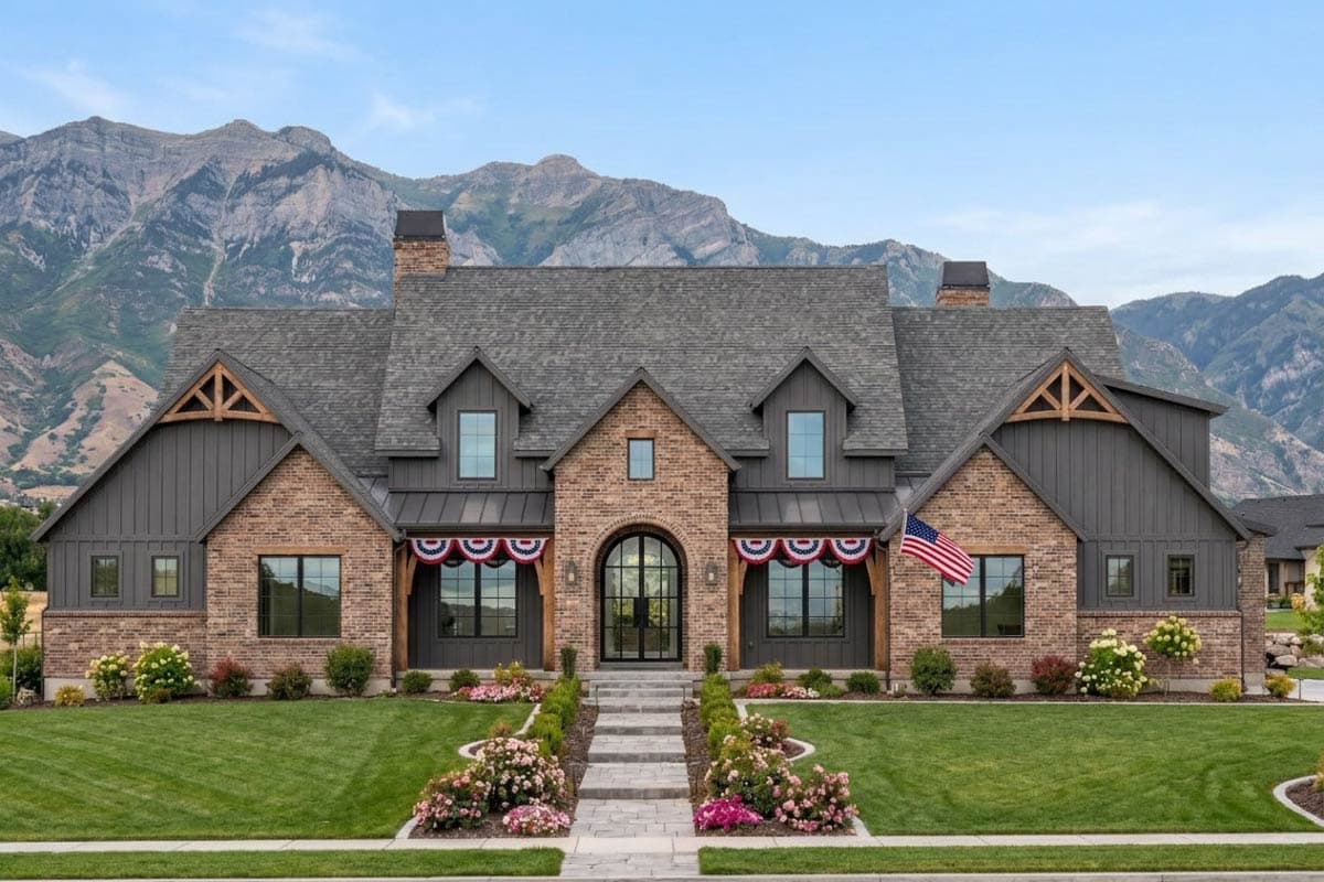 House plan exterior: Brick and dark siding, gabled dormers, decorative trusses, arched entryway with double doors, and prominent chimney.