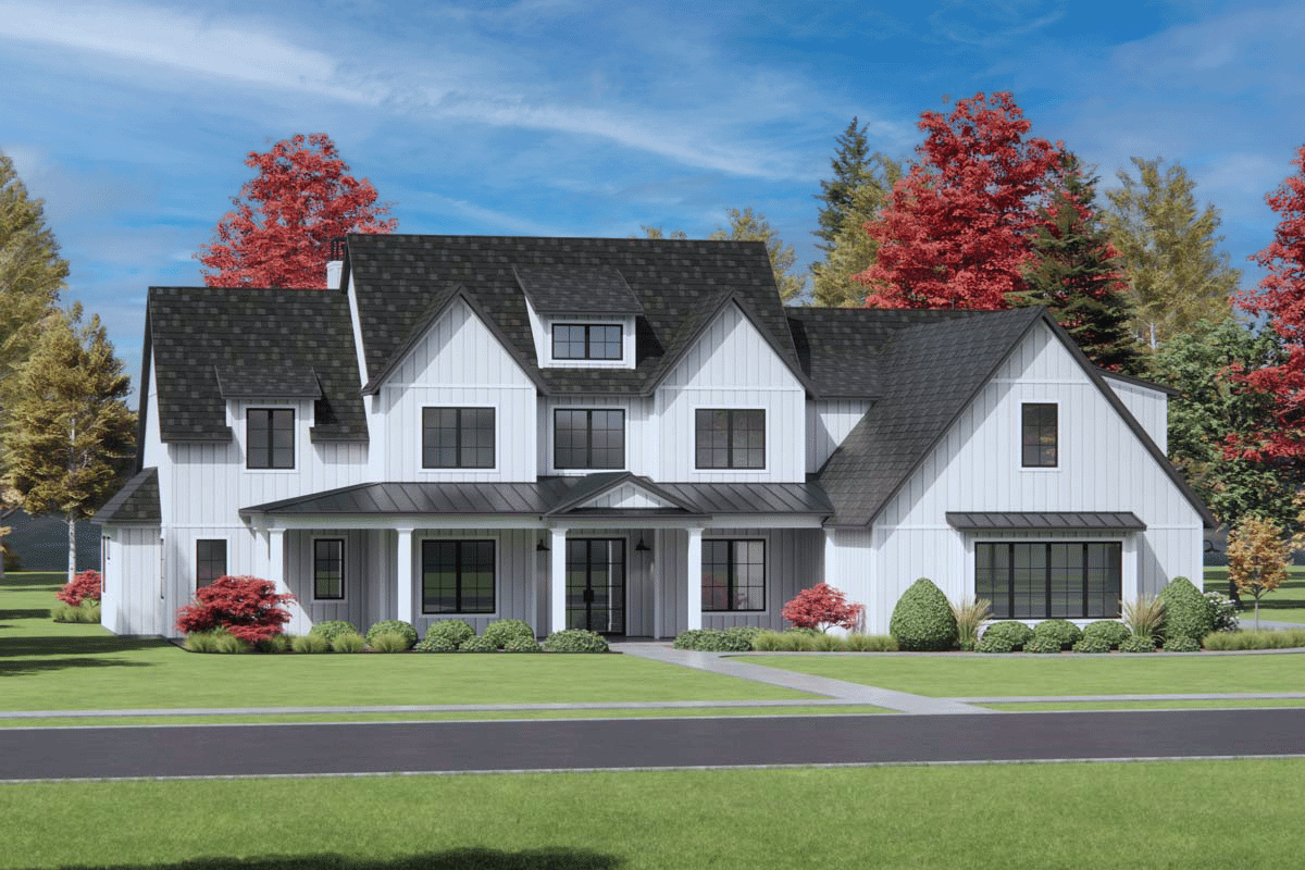 A large white farmhouse with a black roof, windows, and trim. The home has a long front porch and sits on a green lawn with a tree-lined background.