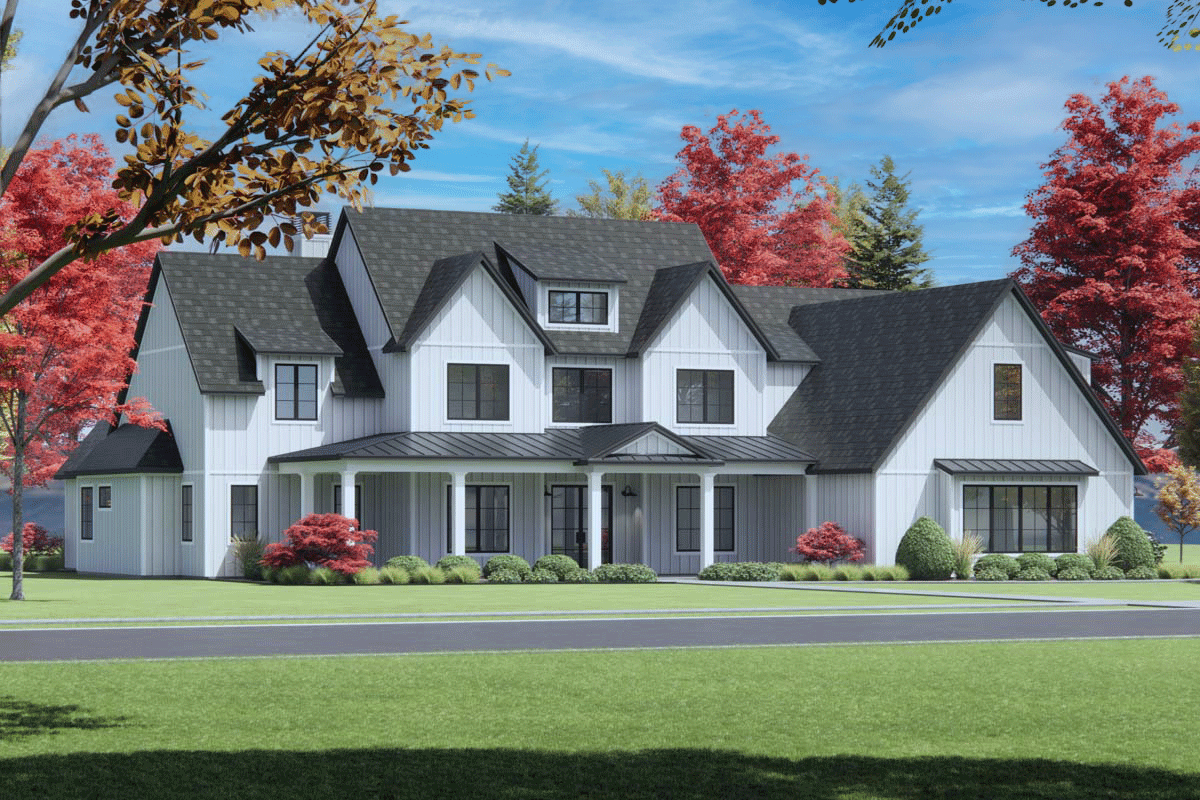 A large, modern farmhouse with a white exterior, black roof, and porch. The house is surrounded by green lawn, bushes, and trees with fall foliage.