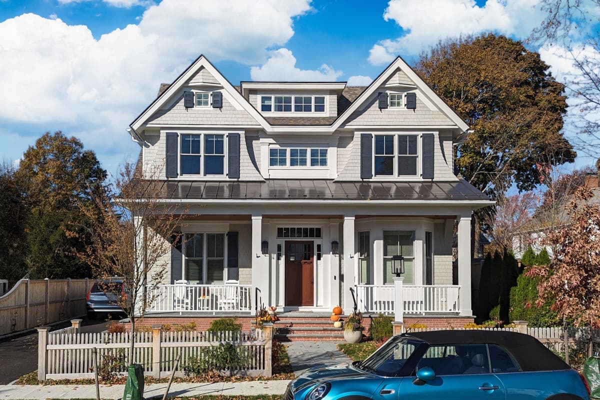 House plan exterior, two-story home with gabled dormers, wide front porch, bay window, and prominent central entrance.
