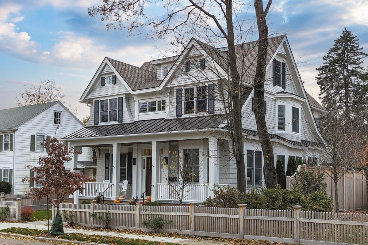 House plan exterior: two-story with covered front porch, gables, dormers, and a bay window.