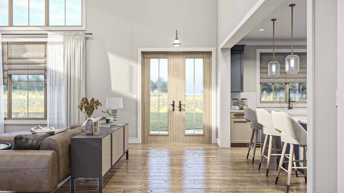 Interior view of a house showing a living area with leather sofa and a kitchen with island and bar stools.