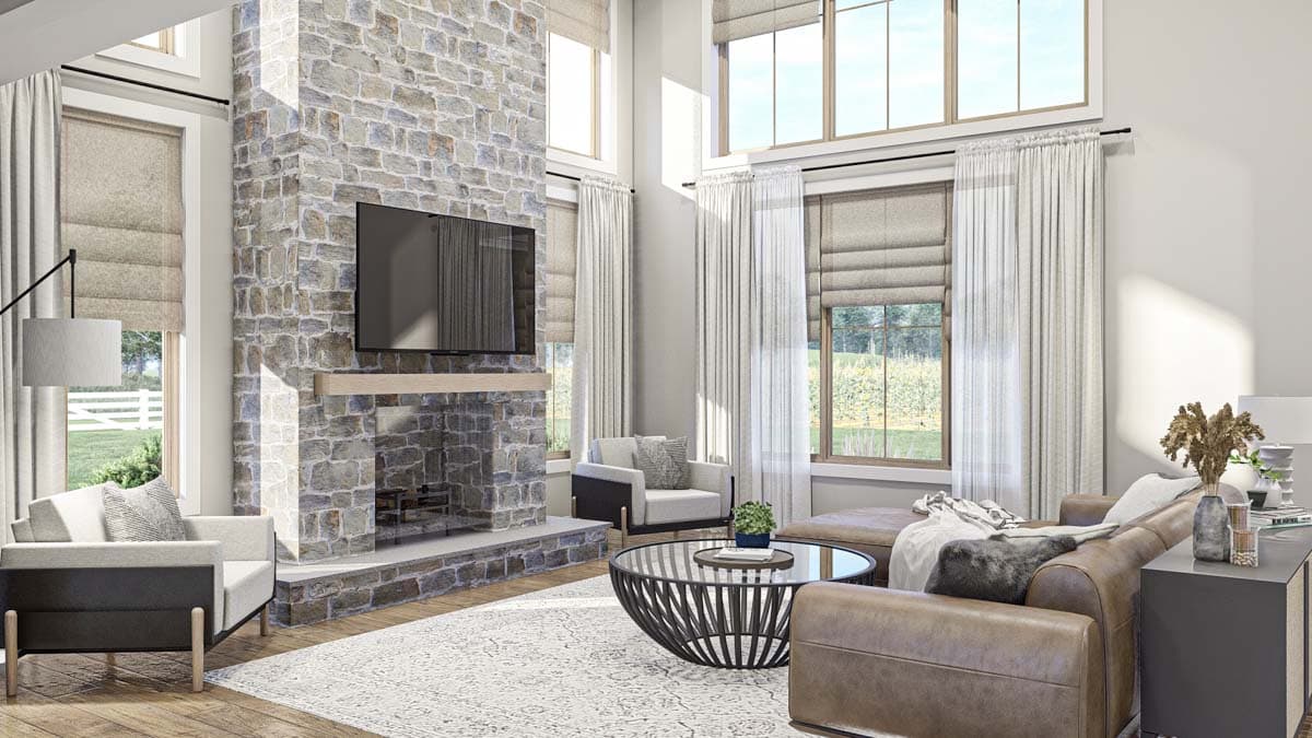 Living room interior with floor-to-ceiling stone fireplace, vaulted ceiling, and large windows.