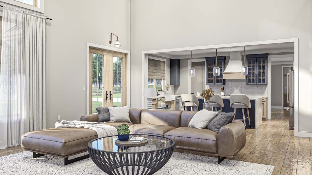 Open-concept living area with sectional sofa, coffee table, and adjacent kitchen with island and bar stools.