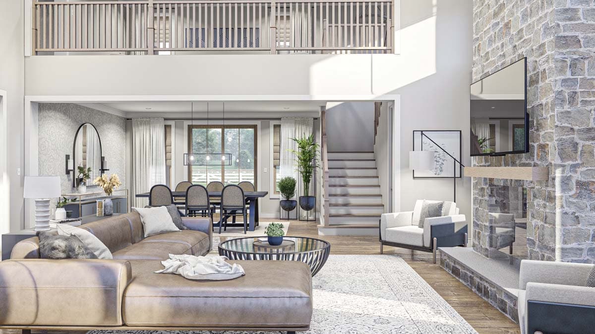 Interior view of open-concept living space with sectional sofa, dining area, stone fireplace, and lofted second floor.