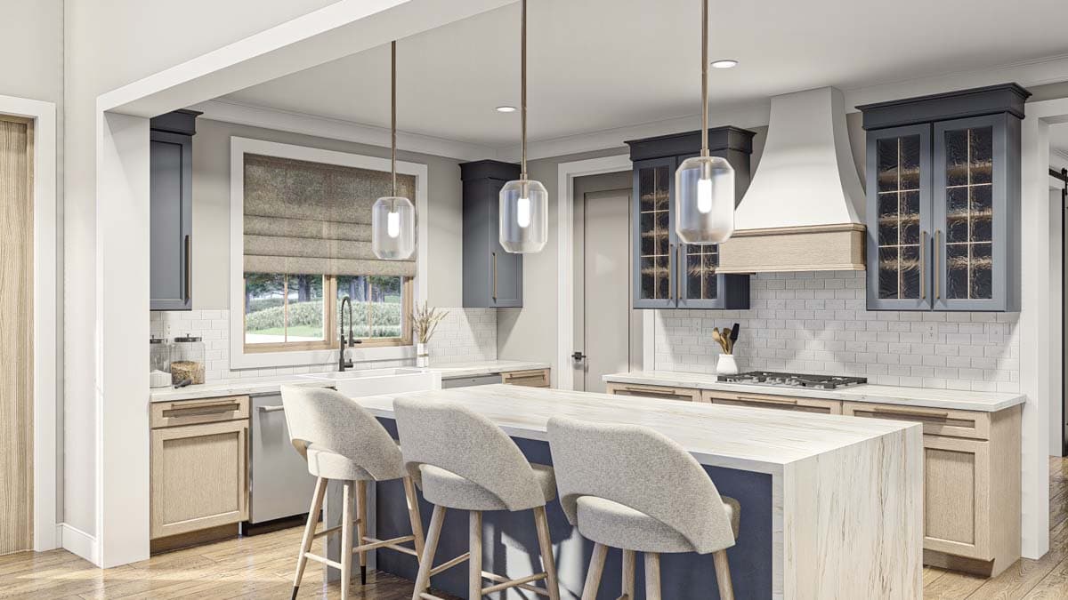 Kitchen interior with island, gray cabinets, white subway tile backsplash, range hood, and pendant lights.