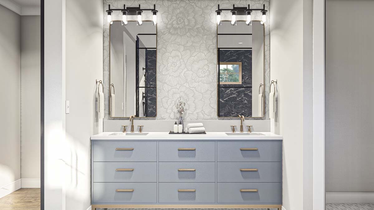 Bathroom vanity with double sinks, brushed gold fixtures, floral wallpaper, and gray cabinetry.