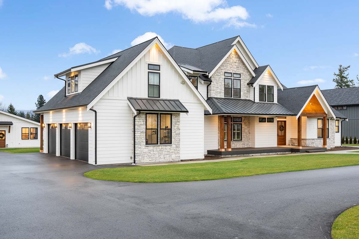 Modern Farmhouse style house plan exterior with white siding, stone accents, a covered porch, and a three-car garage.