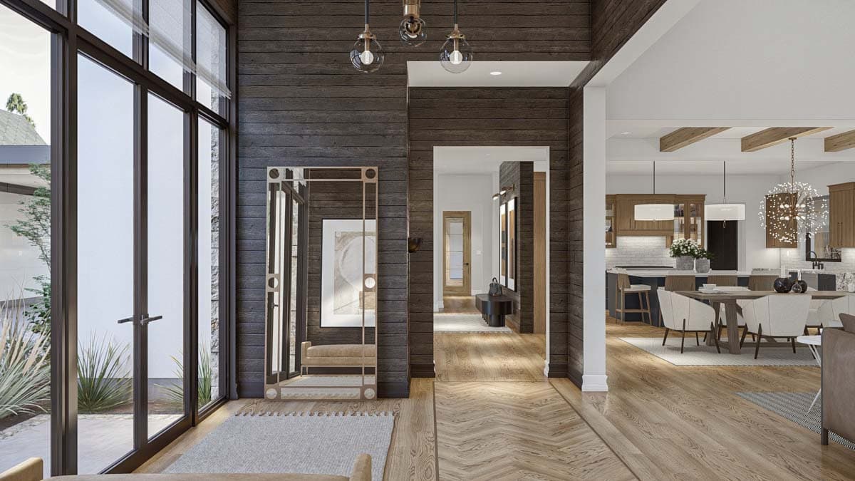 Interior view of a modern house entrance hall with wood plank walls, large windows, and open view to kitchen and dining area.