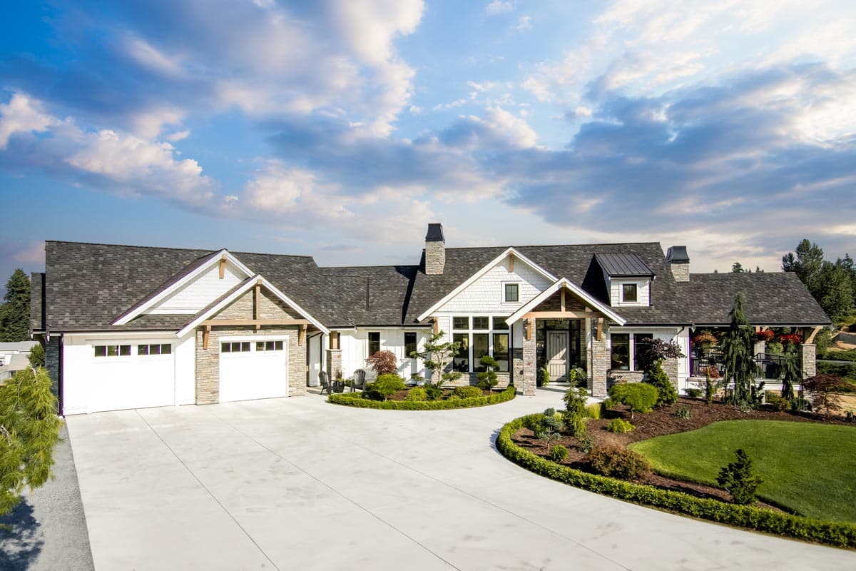 House plan exterior featuring a two-story Craftsman style home with gables, stone accents, and a front-entry porch. Attached garage to the left.