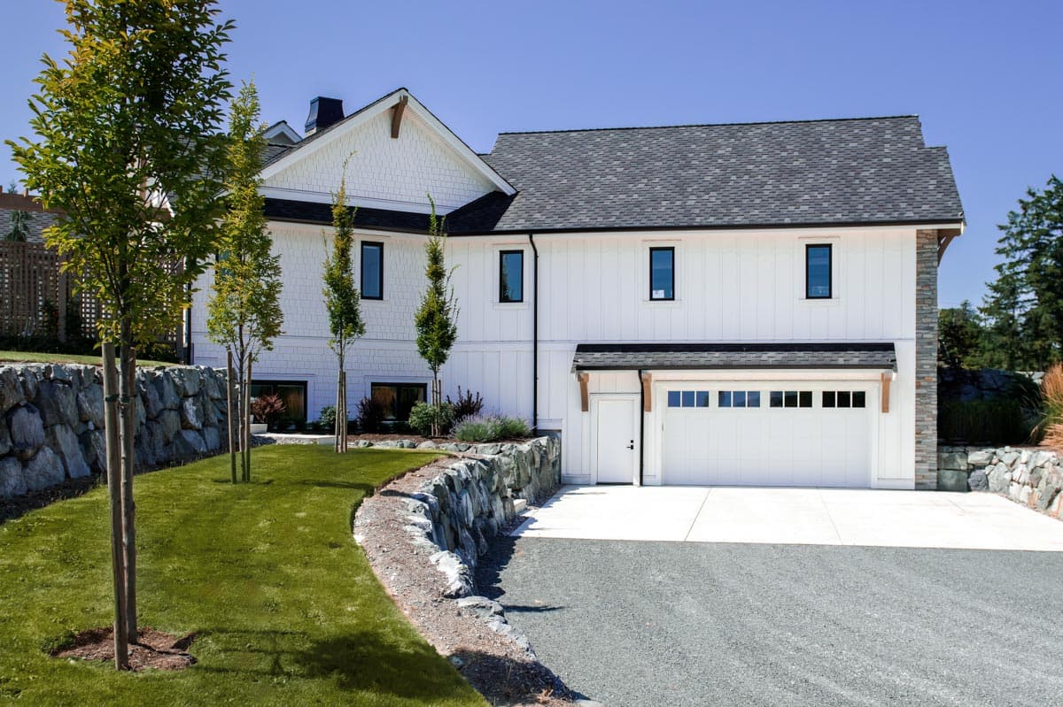 Two-story Modern Farmhouse exterior with white vertical siding, decorative gables, and a double garage.