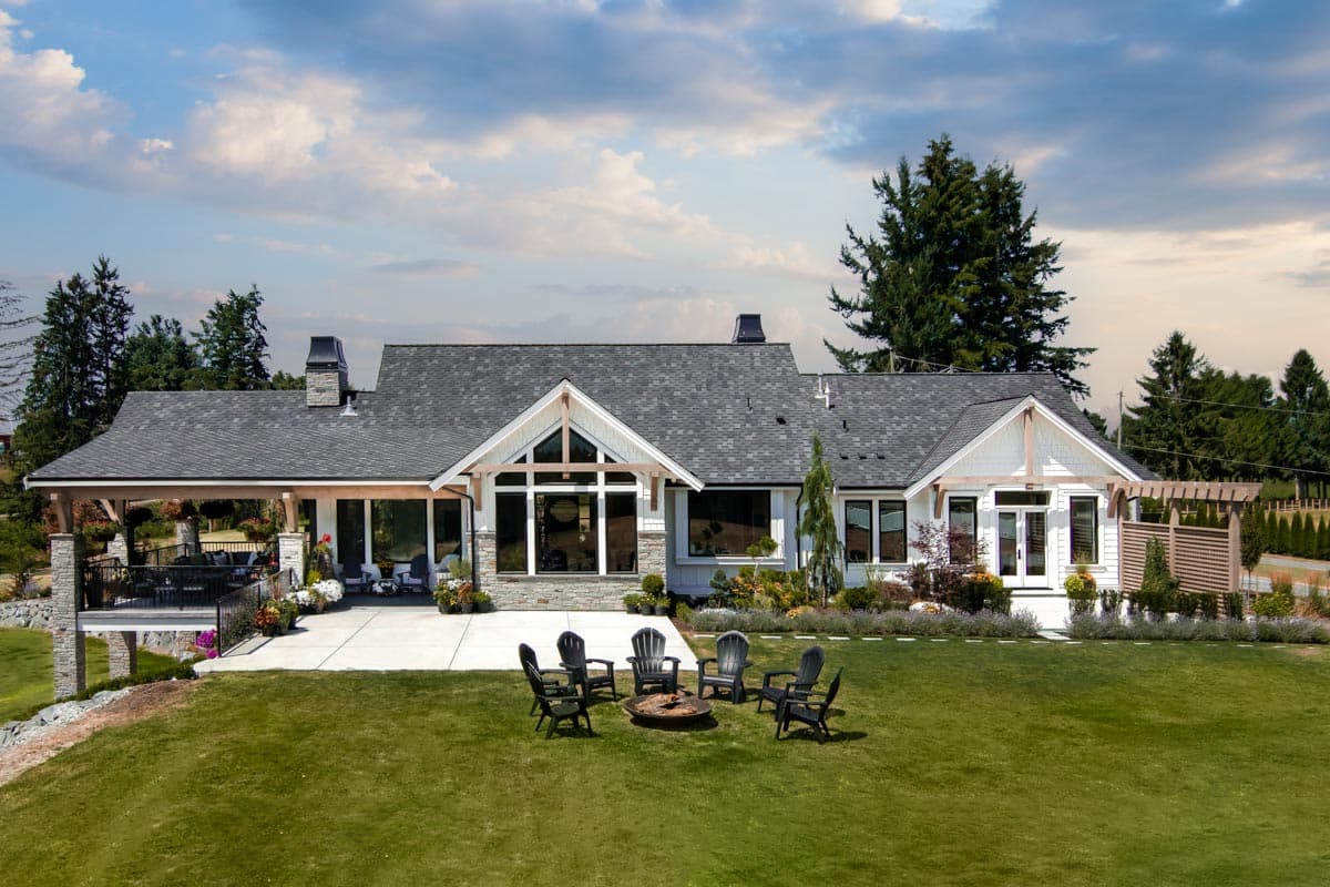 Modern Farmhouse house plan exterior with a covered deck, gables, stone accents, and large windows.