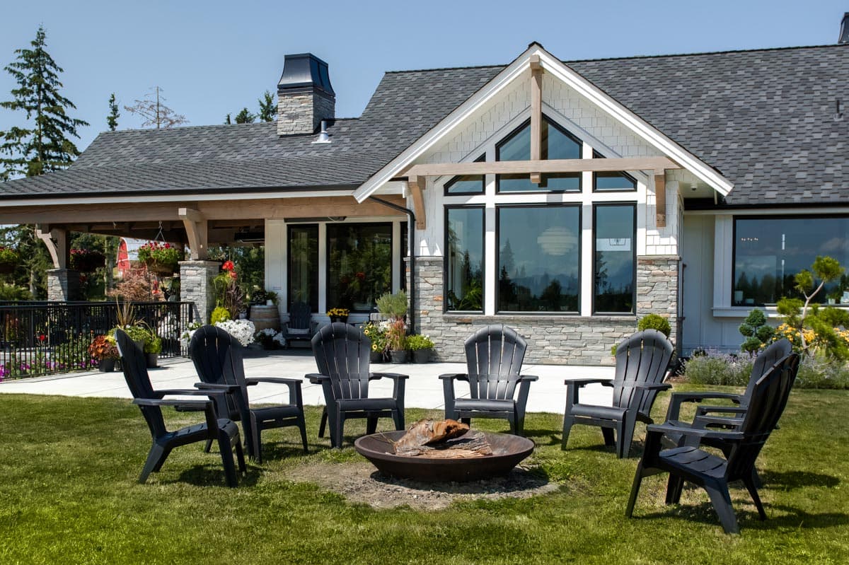 House plan exterior featuring a covered porch, stone and shingle siding, and a prominent gable with large windows.
