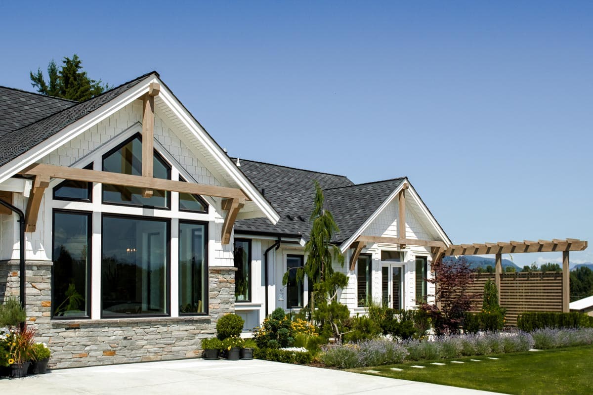 House plan exterior featuring gables with exposed beams, stone base, and large windows. Modern Farmhouse style.