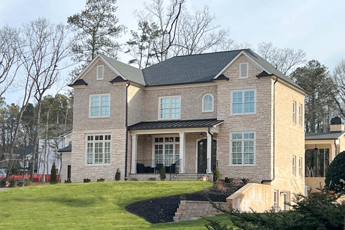 House plan exterior: Two-story dwelling with stone and stucco facade, gables, and covered front porch.