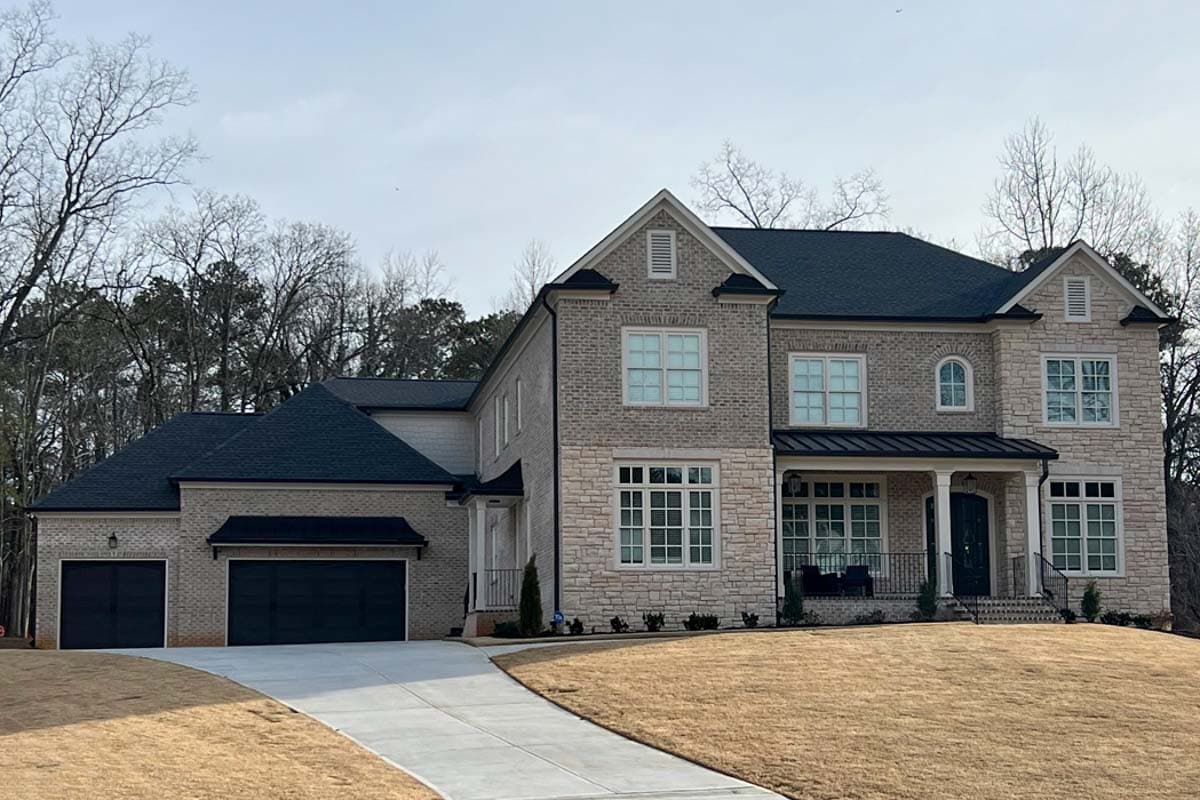 Two-story house plan exterior with brick and stone facade, dark gable roof, and attached three-car garage.