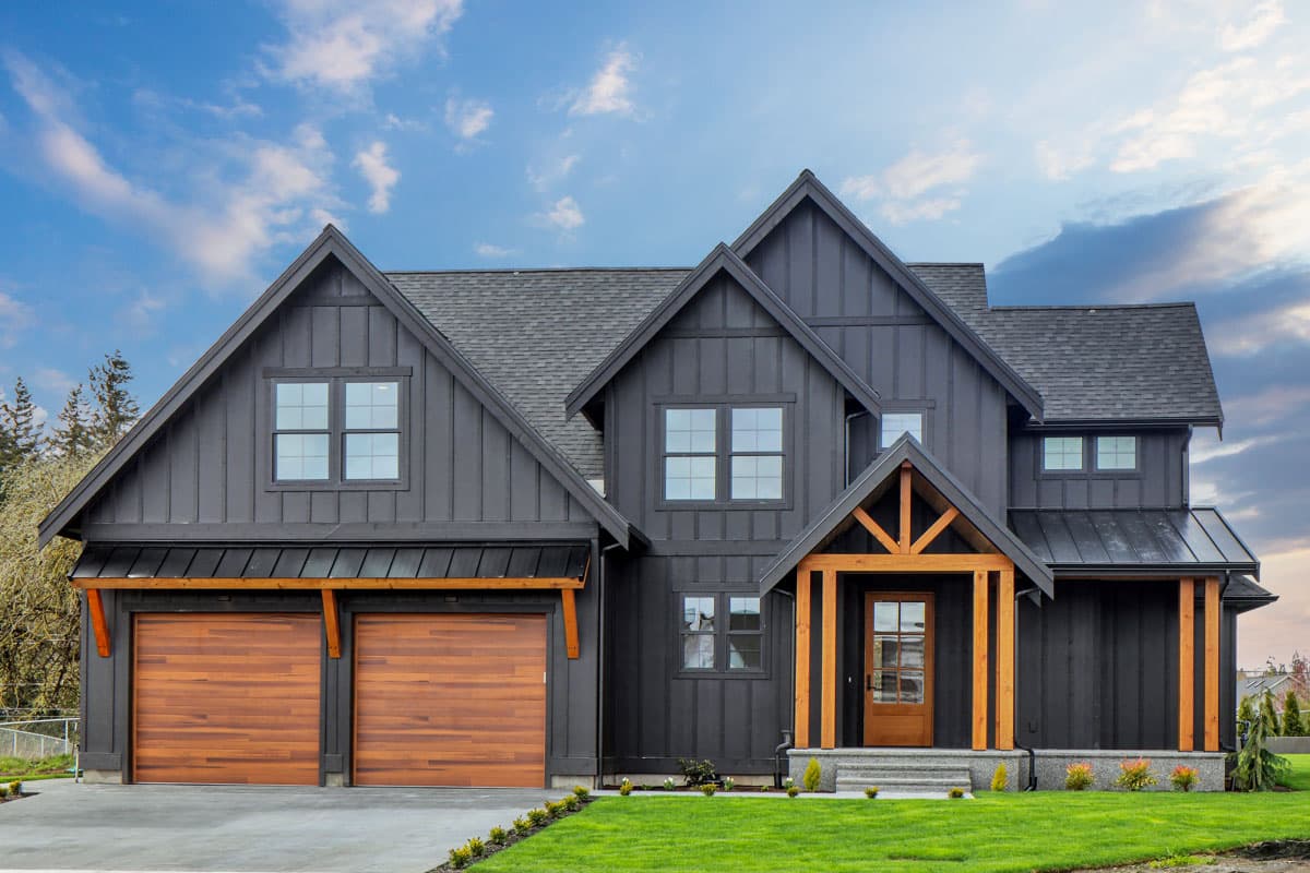 House plan exterior. Two-story Modern Farmhouse with gables, a covered entry porch, and a two-car garage with wood doors.