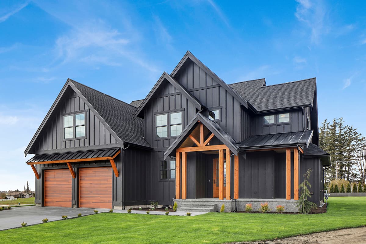 Modern Farmhouse exterior with dark board and batten siding, exposed wood beams on entryway, and double garage doors.