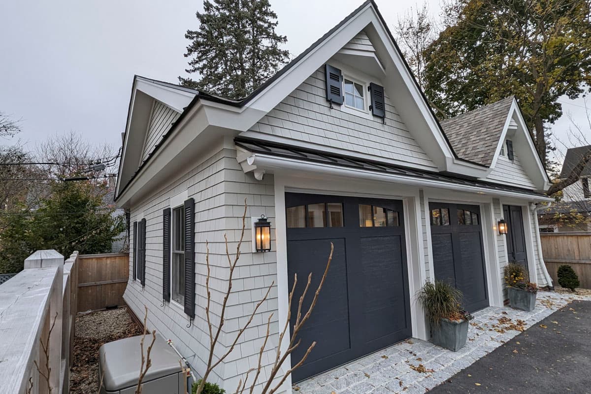 Modern Farmhouse house plan exterior, 2 stories, white shake siding, gables with dormers, and dark garage doors.