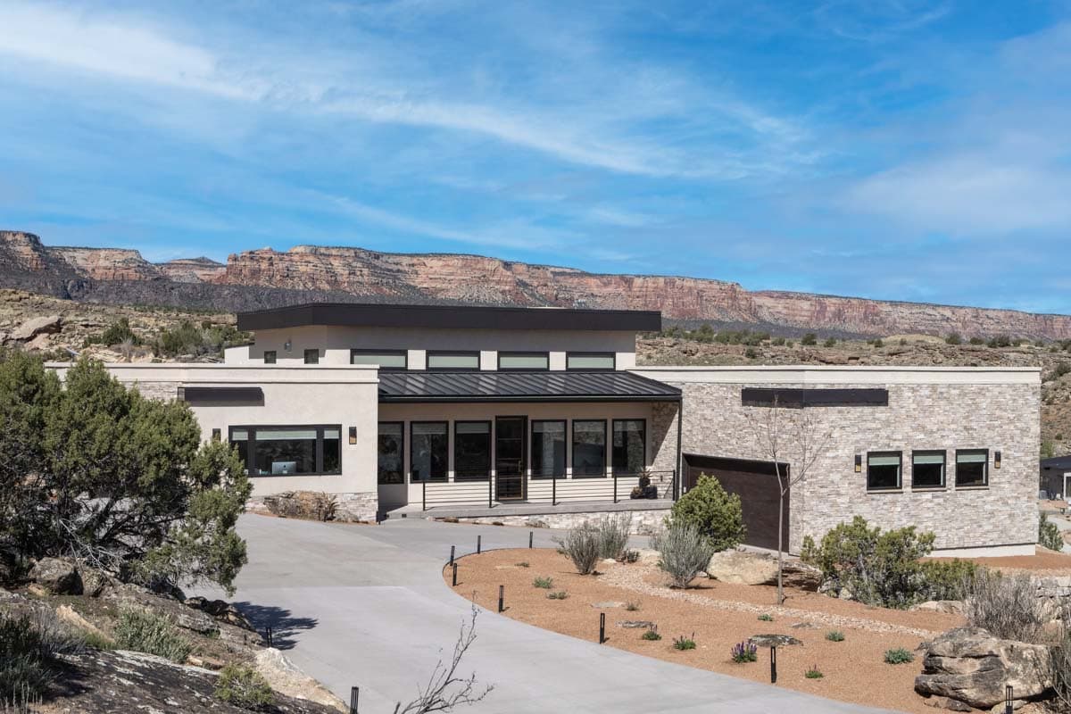 Modern house plan exterior featuring stucco, stone, flat roof, and large windows. Includes a two-car garage.