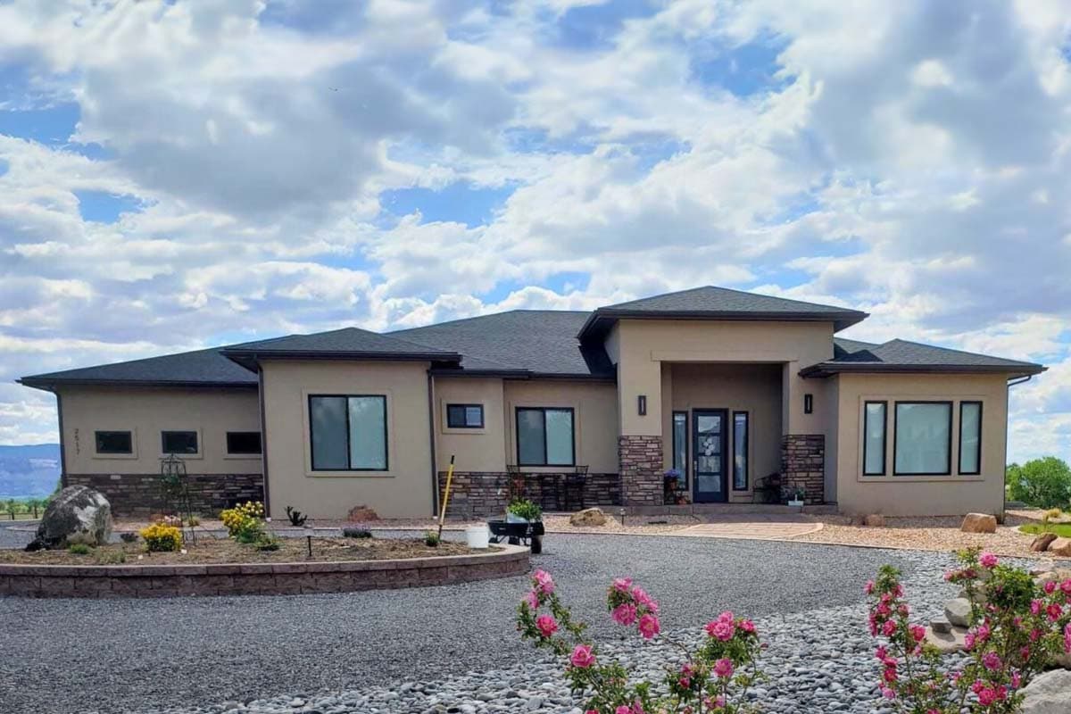 House plan exterior of a single-story modern home with a stucco finish, stone accents, and a prominent covered entryway.