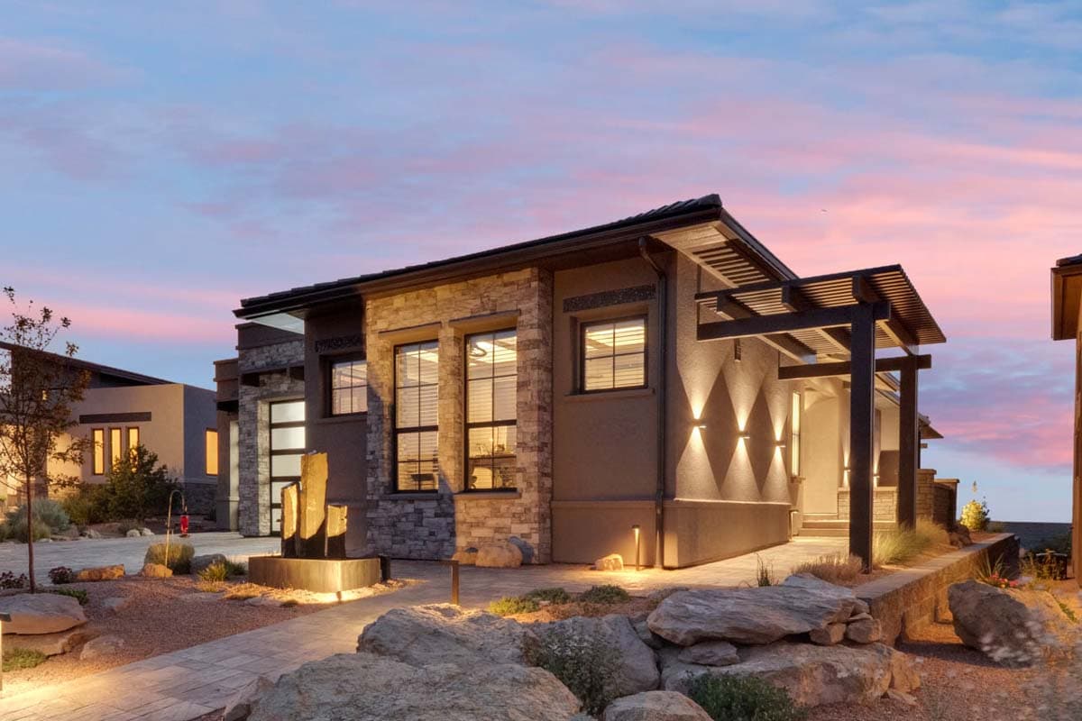 Modern house plan exterior with stone accents, large windows, covered entryway with pergola, and integrated lighting.