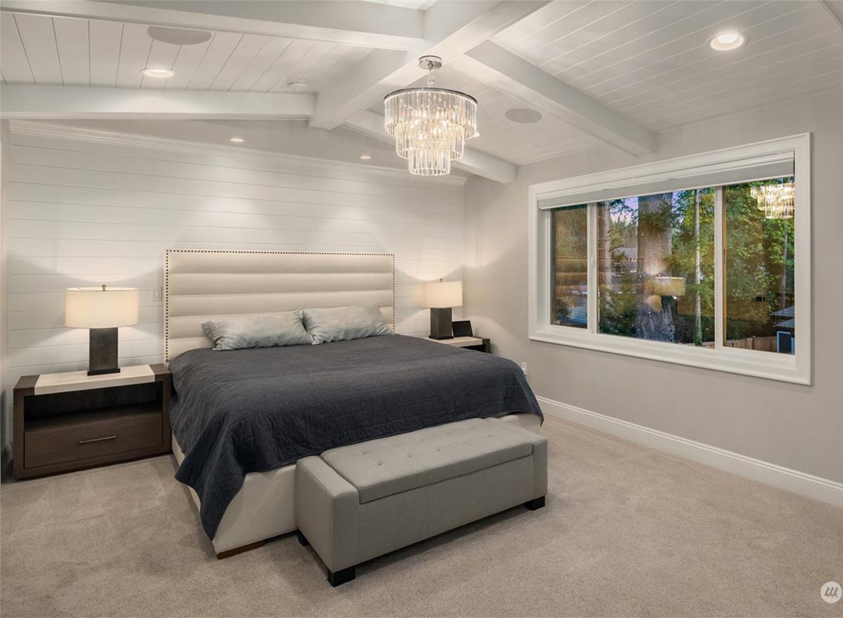 Bedroom interior with paneled walls, coffered ceiling, large window overlooking trees, and tufted headboard.