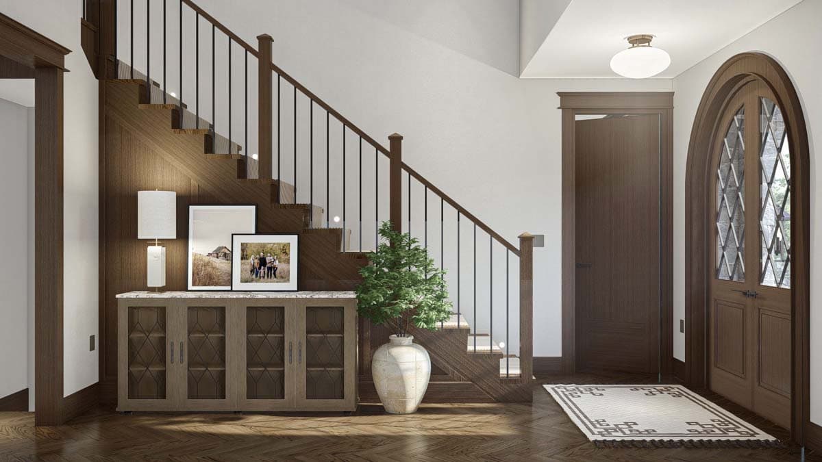 Interior view of a house entrance with a wooden staircase, console table, and arched double doors with decorative glass.