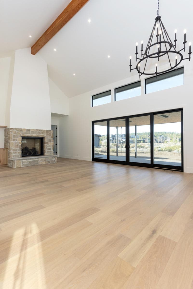 Spacious, modern living room with hardwood floors, a stone fireplace, and large sliding glass doors leading to a patio.