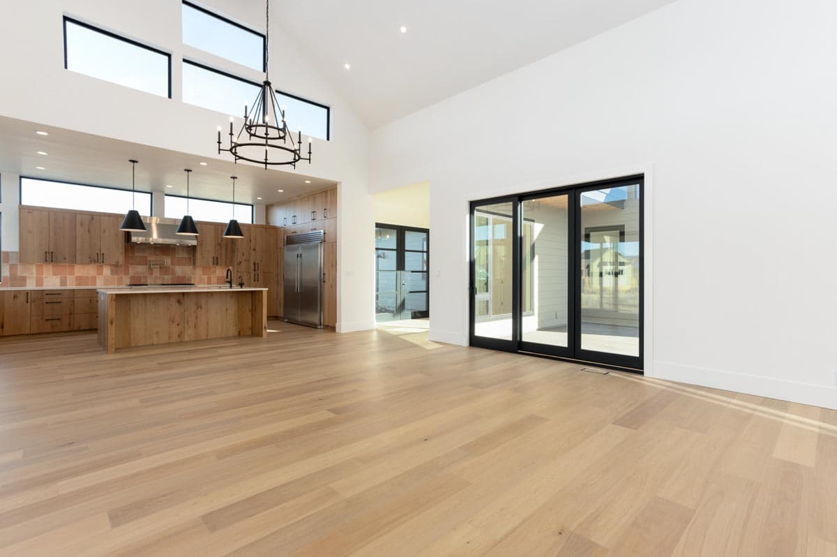 Spacious, modern kitchen with light wood cabinets, an island, and large windows. Sliding glass doors lead to an outdoor area with natural light.