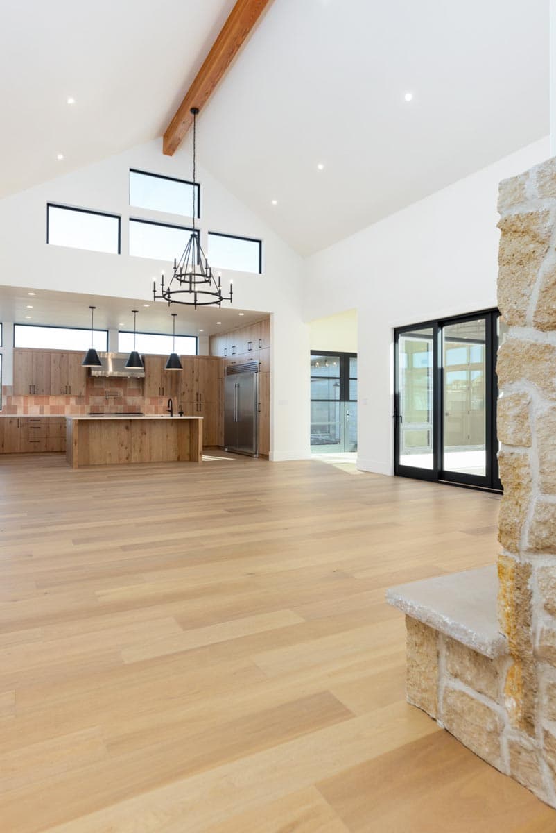 Spacious, modern kitchen with hardwood floors and vaulted ceiling. A large island and wood cabinetry contrast with stainless steel appliances.