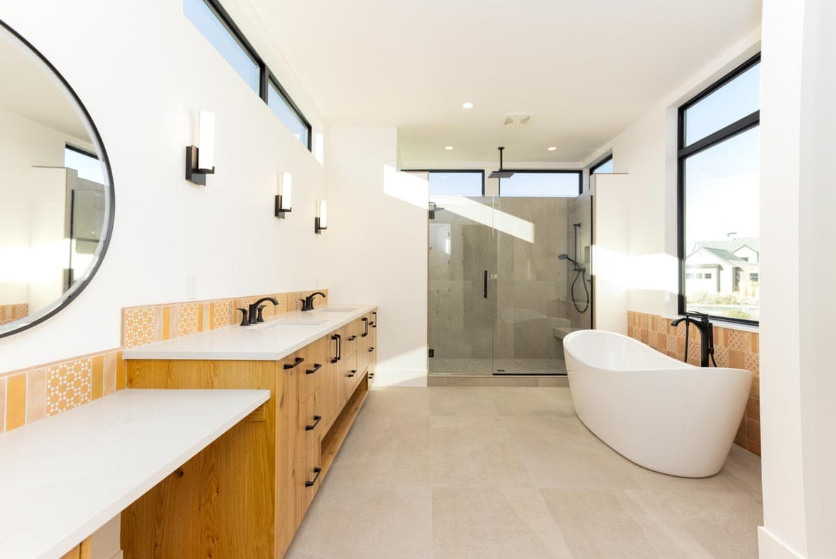 Modern bathroom featuring a freestanding tub, a walk-in shower, and a wooden vanity with double sinks, all with contemporary black fixtures.