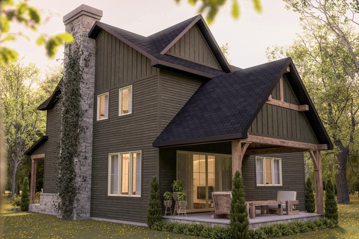 Exterior of a modern home with dark siding, a stone chimney, and a porch.