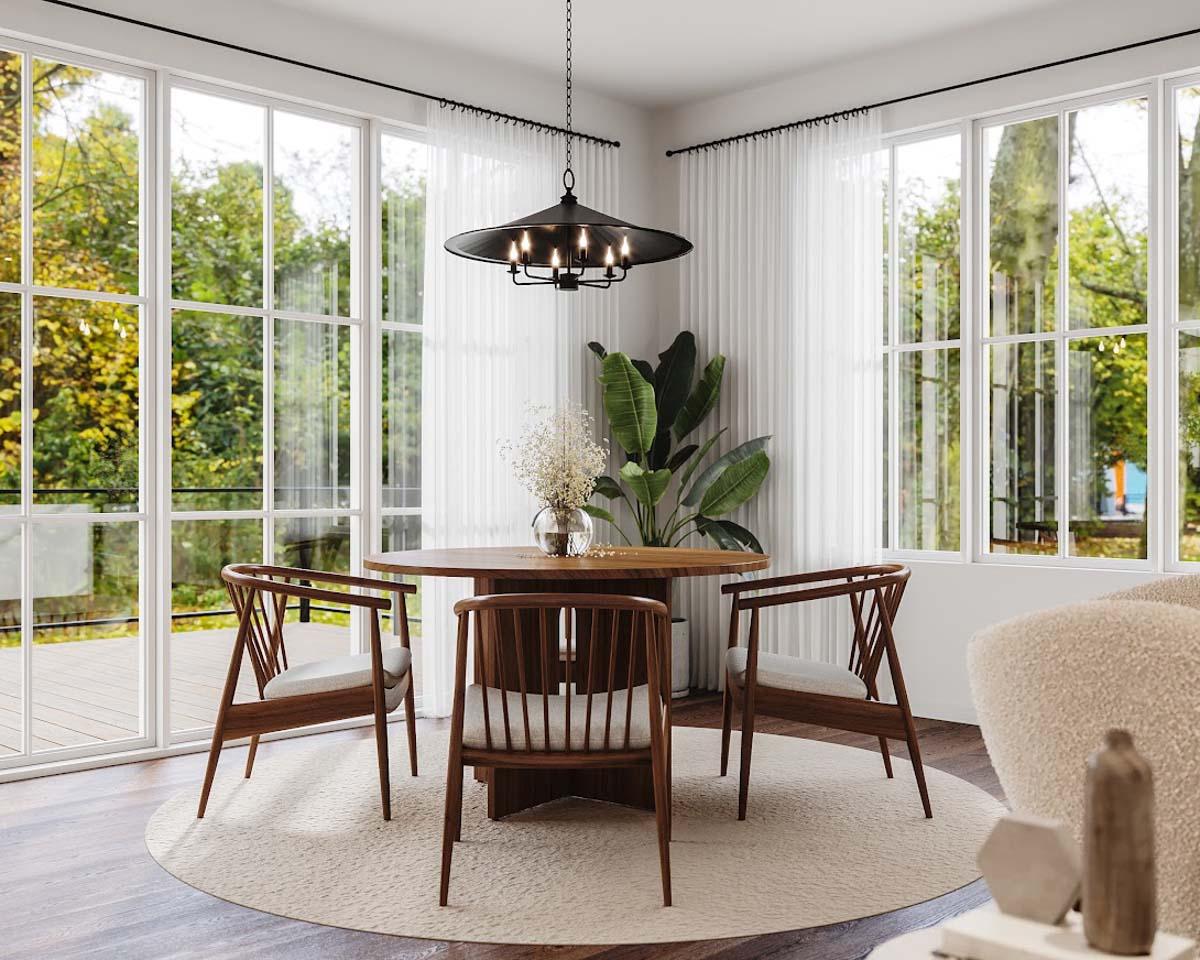 Elegant dining room with wooden chairs and a round table under a chandelier. Large windows offer a view of greenery.