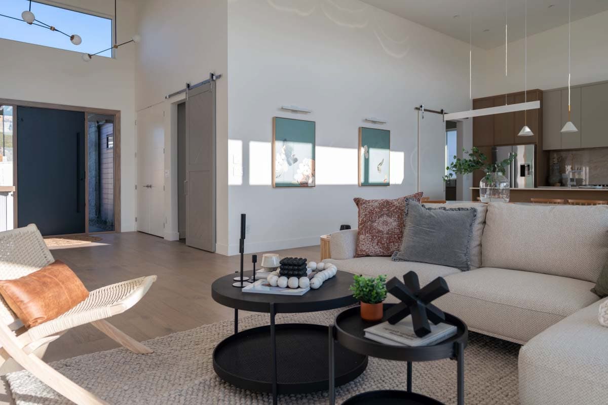 Interior rendering of an open-concept living area with a sectional sofa, modern fireplace, and sliding barn doors.