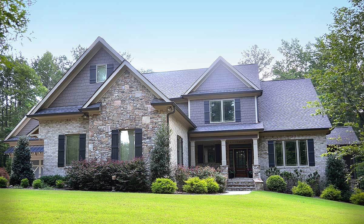 House plan exterior: Two-story home with stone and brick facade, gabled dormers, and covered entry porch.