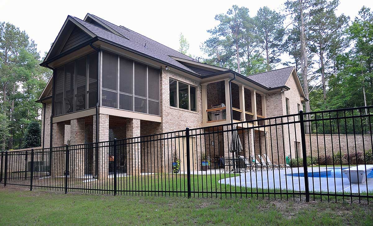 House plan exterior with brick facade, multi-story design, large screened porch, covered balconies, and a pitched roofline.