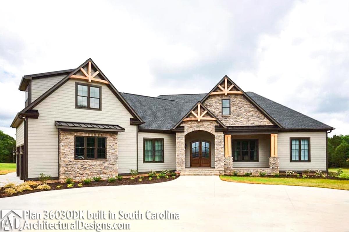 House plan exterior: one-story home with stone accents, prominent gables, exposed wood beams, arched entry, and covered porch.
